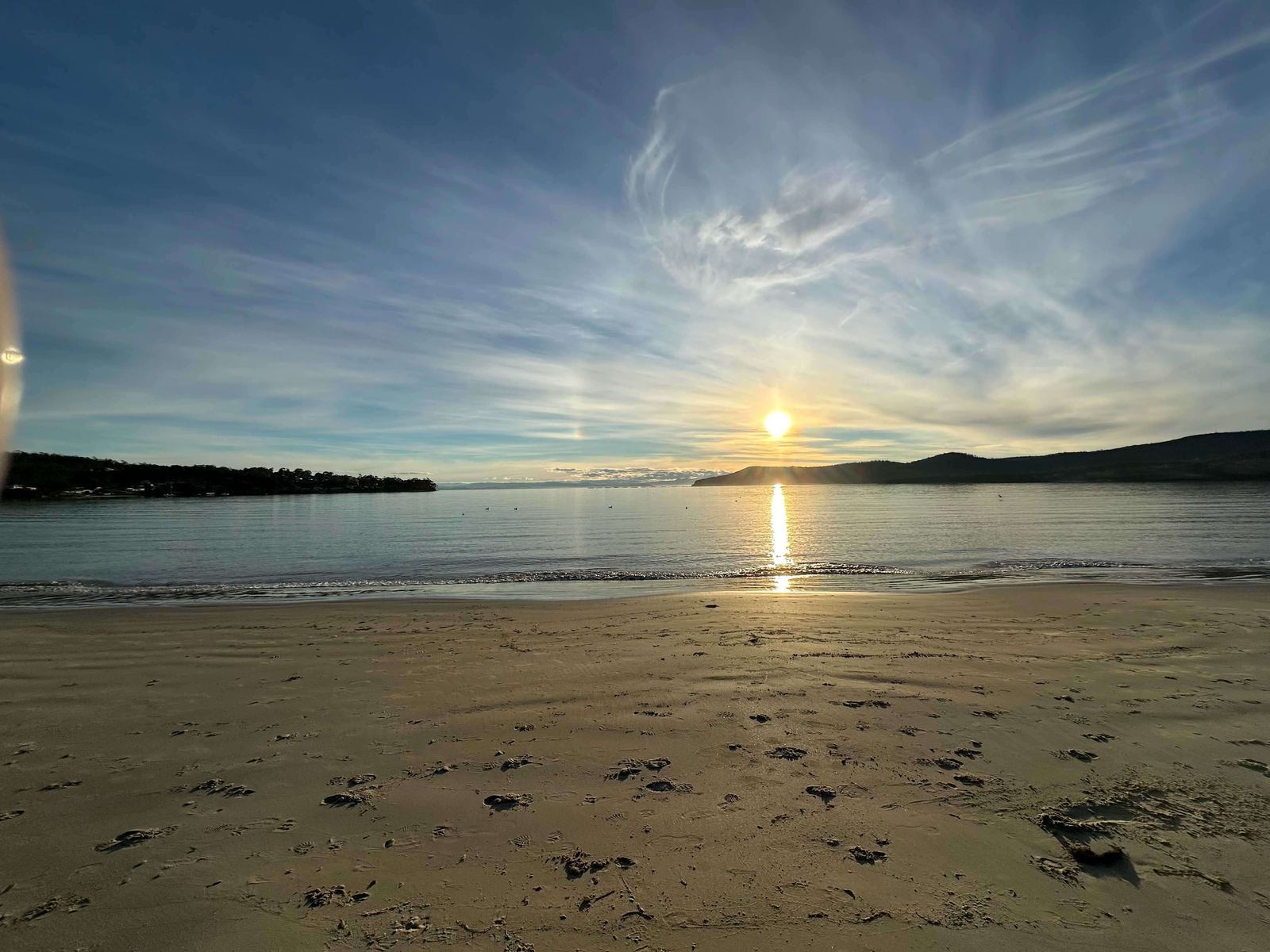 Warm golden-hour light on smooth sand and calm water — the tone the soaks are made to complement.